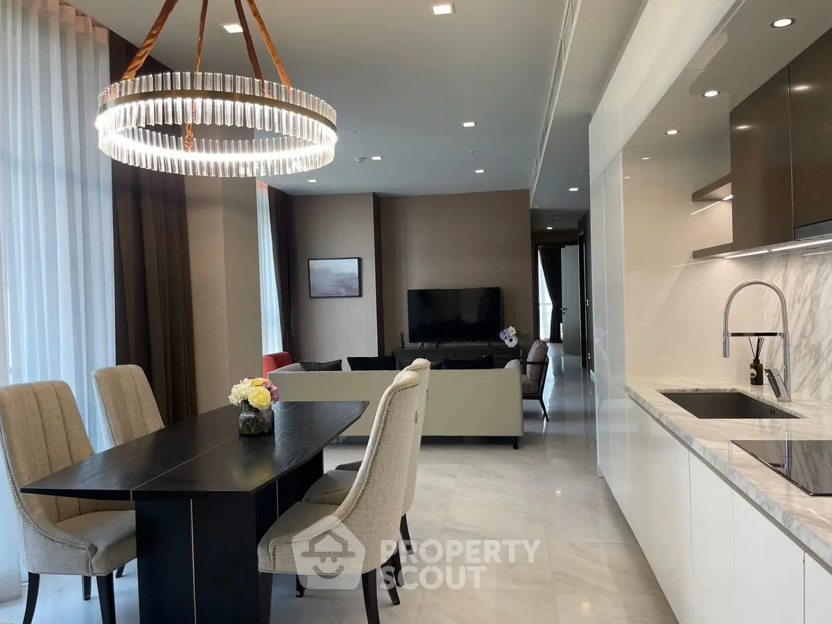 Luxurious open-plan living and dining area with modern chandelier and sleek kitchen.