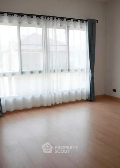 Spacious empty room with large windows and wooden flooring, perfect for customization.