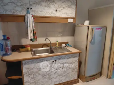 Compact kitchen with marble-patterned cabinets and a small fridge, ideal for cozy apartments.
