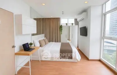 Modern bedroom with large windows and city view, featuring sleek furniture and neutral decor.