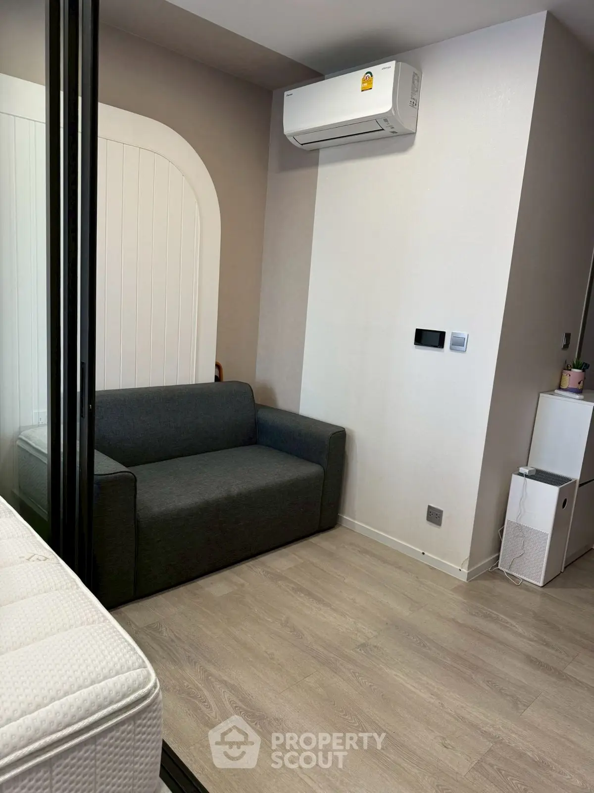 Modern compact living room with sleek sofa and air conditioning unit, perfect for urban living.