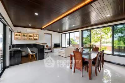 Spacious modern living room with open kitchen and dining area, featuring large windows and elegant decor.