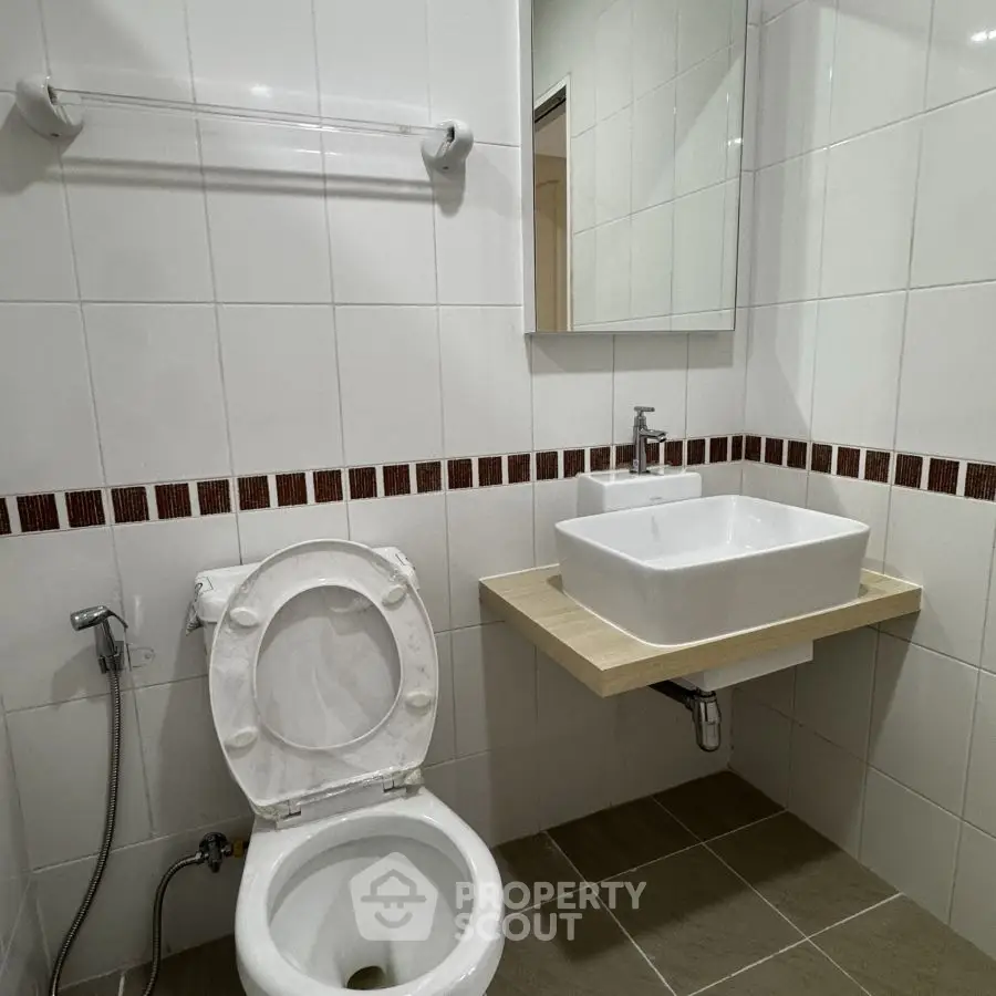Modern bathroom with white tiles and square sink in a sleek design.