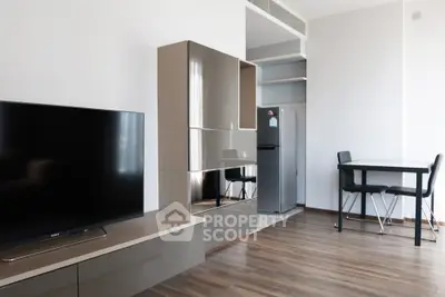 Modern living room with sleek furniture and dining area, featuring a flat-screen TV and stylish flooring.