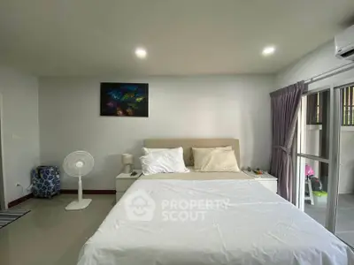 Spacious bedroom with modern decor and large window for natural light