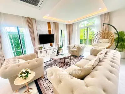 Luxurious living room with elegant furniture and large windows offering garden views.
