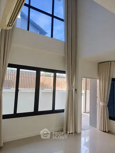 Spacious modern living room with high ceilings and large windows offering natural light.