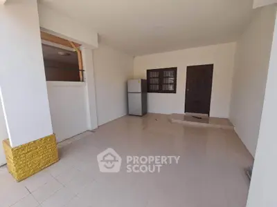 Spacious tiled entrance area with fridge and door, ideal for versatile use.