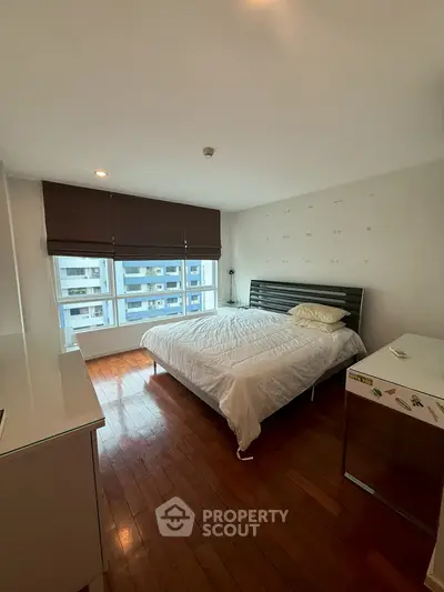 Spacious bedroom with wooden flooring and large window in modern apartment