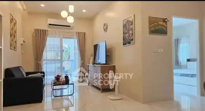 Modern living room with sleek furniture and large TV, featuring elegant lighting and a view of the balcony.
