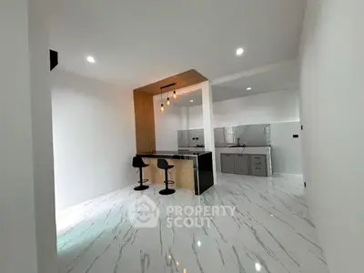 Modern kitchen with sleek marble flooring and stylish breakfast bar in open layout design.
