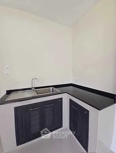 Modern kitchen with sleek black countertops and dual sink in a compact corner layout.
