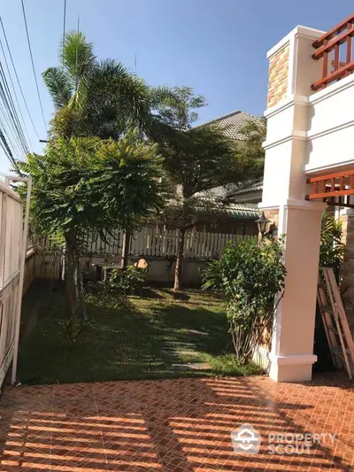 Charming garden view with lush greenery and tiled patio in a serene residential area.