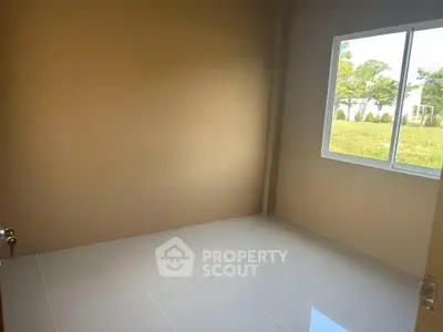 Bright empty room with large window and glossy tiled floor, overlooking lush greenery.