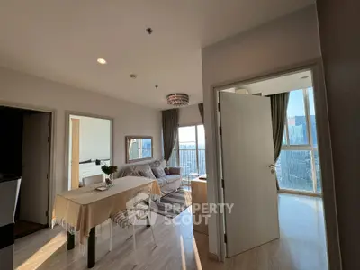 Modern open-plan living room with dining area and large windows offering city views.