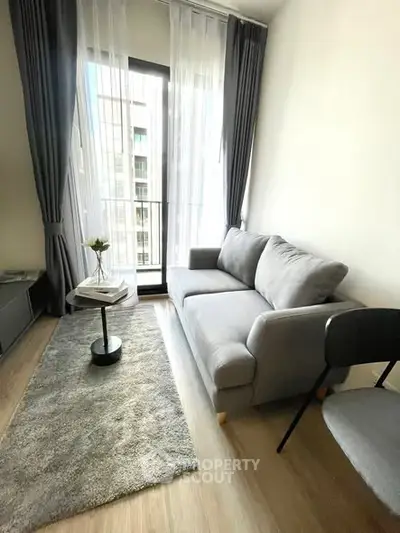 Modern living room with cozy gray sofa and floor-to-ceiling windows.