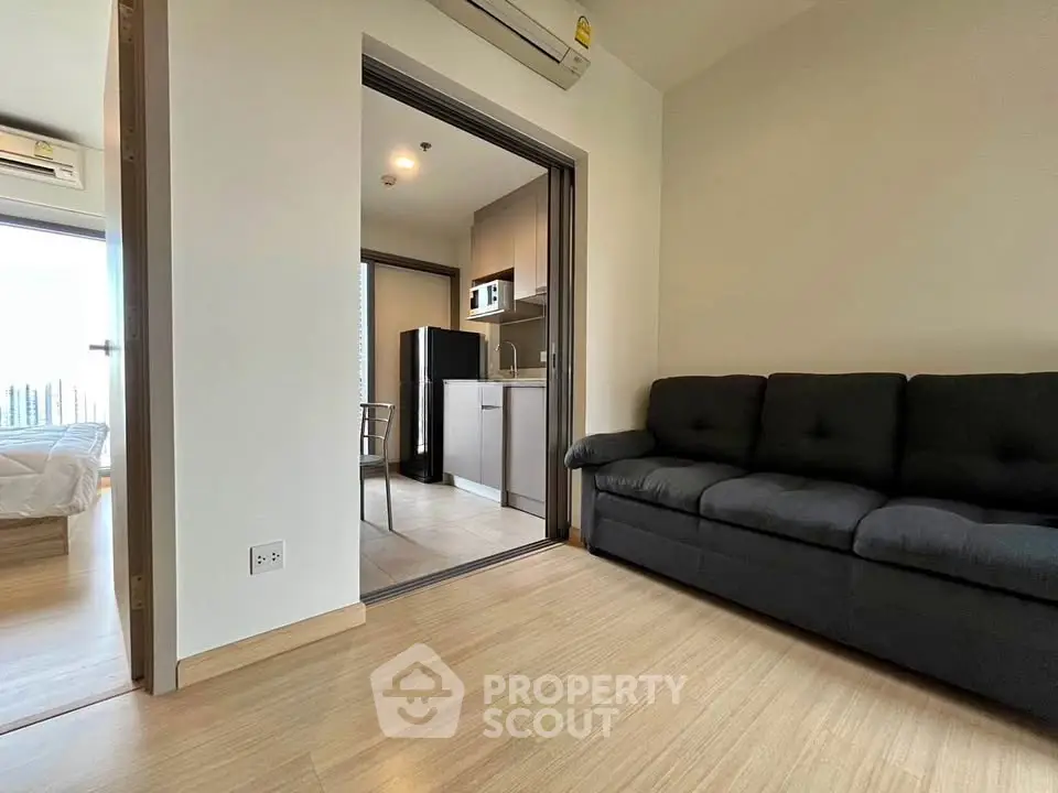 Modern apartment interior with cozy living room and compact kitchen, featuring sleek wooden flooring and stylish furniture.