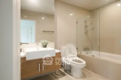 Modern bathroom with sleek fixtures and glass-enclosed bathtub in a stylish apartment.
