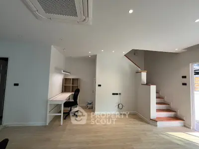 Modern interior with wooden flooring, staircase, and study area with desk and chair.