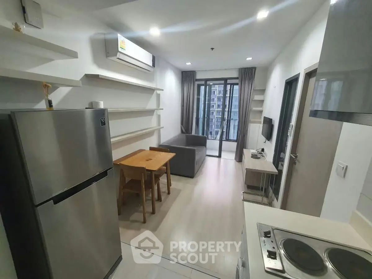 Modern apartment interior with open kitchen and cozy living area, featuring sleek appliances and stylish decor.