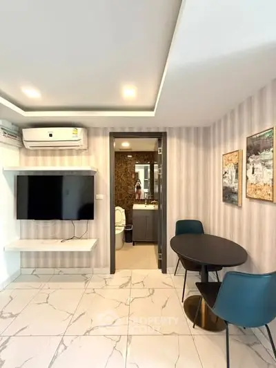 Modern living room with wall-mounted TV and dining area in stylish apartment.