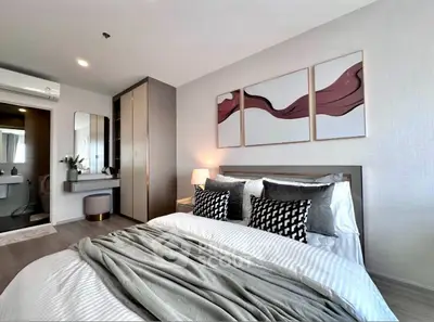 Modern bedroom with stylish decor and cozy ambiance, featuring elegant artwork and plush bedding.