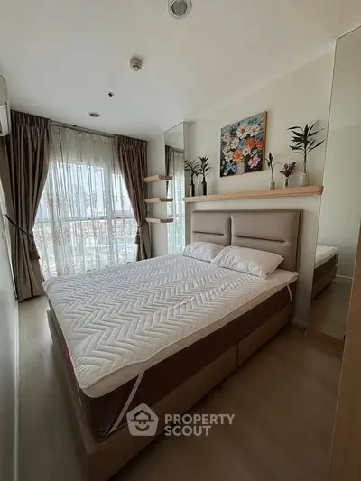 Cozy bedroom with large window and modern decor in a high-rise apartment.