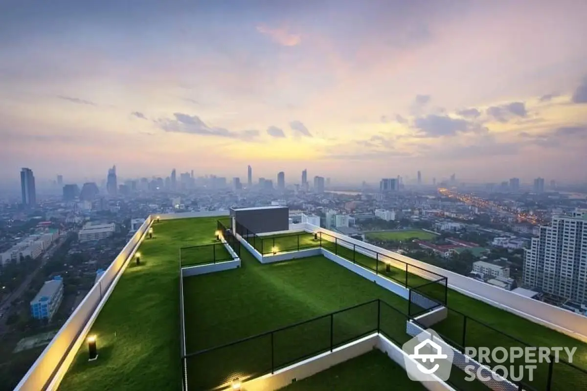 Stunning rooftop view with lush green terrace overlooking city skyline at sunset.