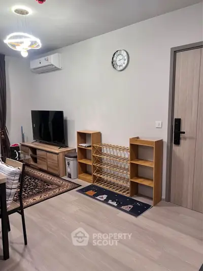 Modern living room with stylish furniture and wall clock, featuring a TV and air conditioning unit.