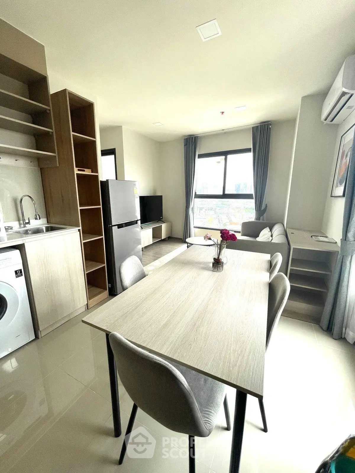 Modern open-plan living room with kitchen, featuring sleek furniture and large window with city view.