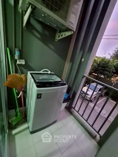 Compact balcony with washing machine and street view, ideal for urban living.