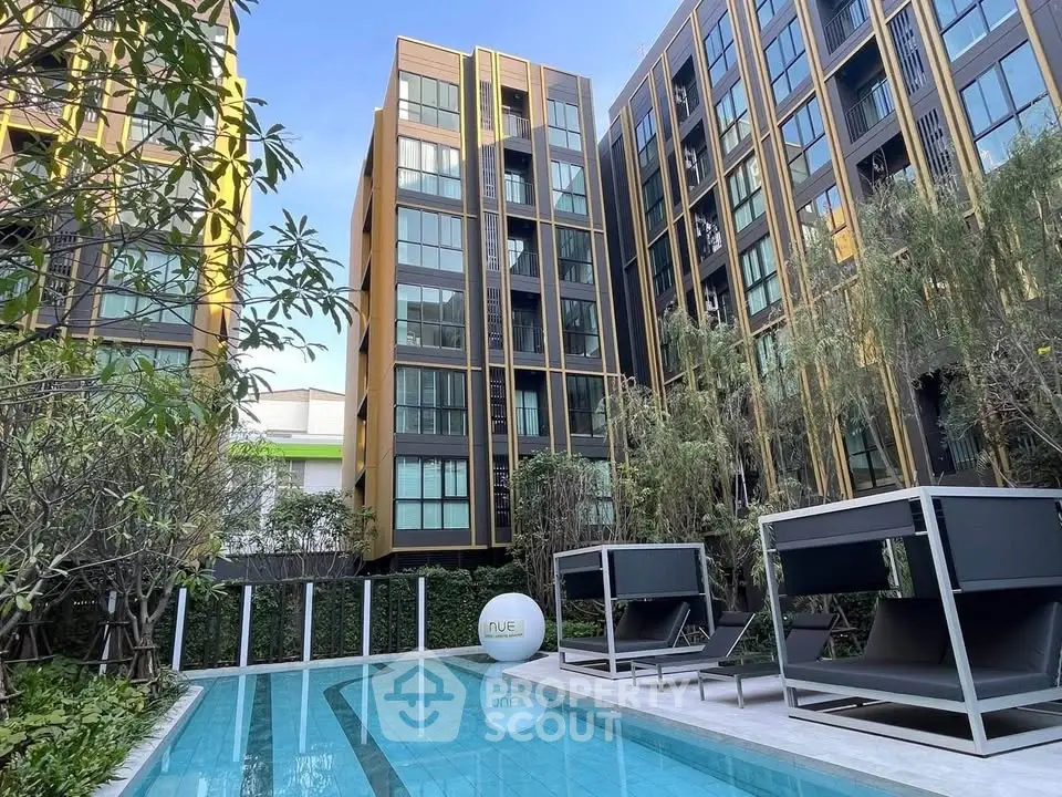 Modern apartment complex with pool and stylish outdoor seating in lush garden setting.
