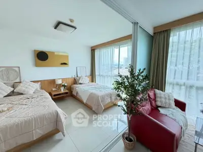 Spacious bedroom with two beds, modern decor, and large windows offering natural light.