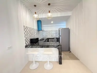 Modern kitchen with stylish bar counter and stools, featuring sleek appliances and elegant lighting.