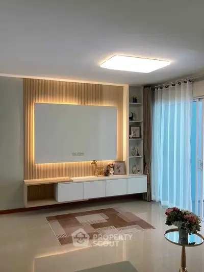 Modern living room with elegant lighting and stylish decor, featuring a sleek TV unit and large window drapes.