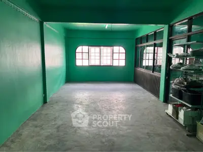 Spacious room with green walls and large windows, ideal for creative workspace or studio.