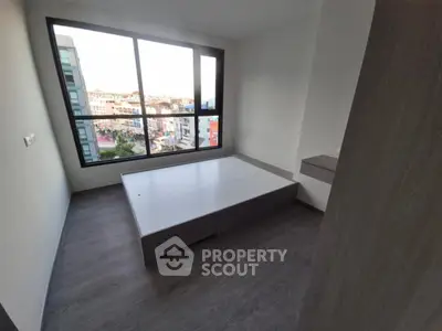 Modern bedroom with large window and city view, featuring sleek flooring and minimalist design.