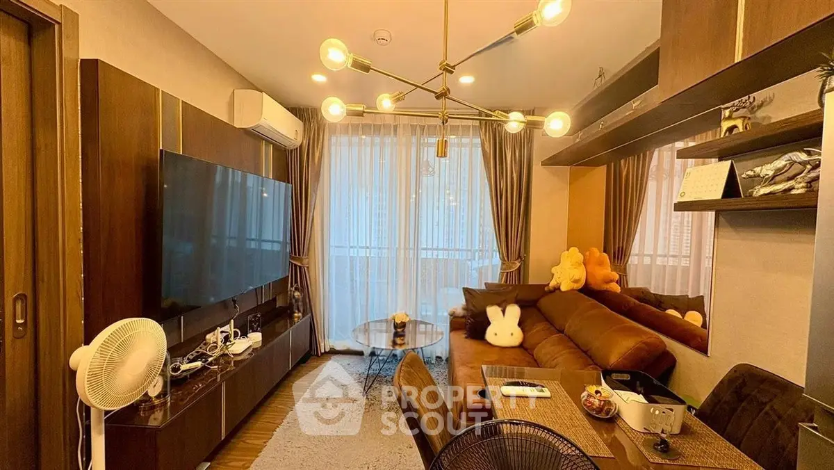 Stylish living room with modern lighting, large TV, and cozy seating area, perfect for relaxation and entertainment.