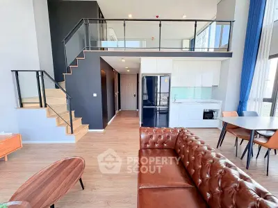 Modern loft apartment with open kitchen and stylish living area featuring leather sofa and dining set.