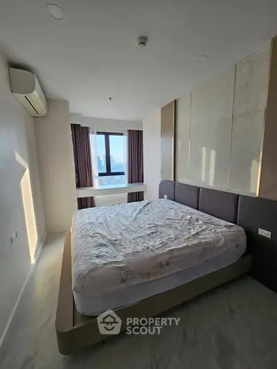 Spacious bedroom with modern design and stunning city view, featuring a large bed and ample natural light.