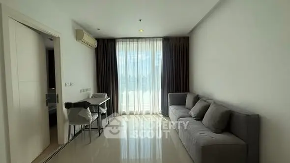 Modern living room with sleek sofa and large window offering natural light.