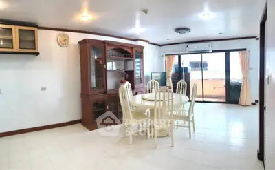 Spacious dining area with elegant wooden furniture and large windows leading to a balcony.