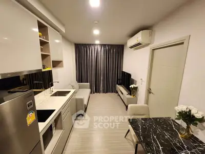Modern living room with sleek kitchen, stylish furniture, and air conditioning in a compact apartment.