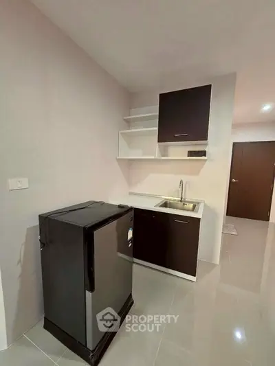 Modern compact kitchen with sleek cabinetry and mini fridge in a stylish apartment.