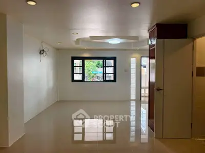 Spacious empty living room with large window and glossy tiled floor