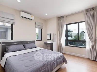 Spacious bedroom with modern decor and large windows offering natural light.