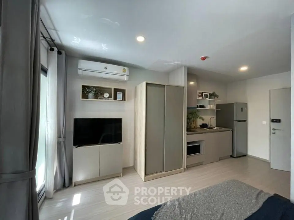 Modern studio apartment with sleek kitchen and cozy living area, featuring natural light and contemporary design.