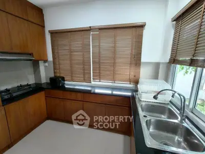 Modern kitchen with wooden cabinets, gas stove, and large window for natural light.