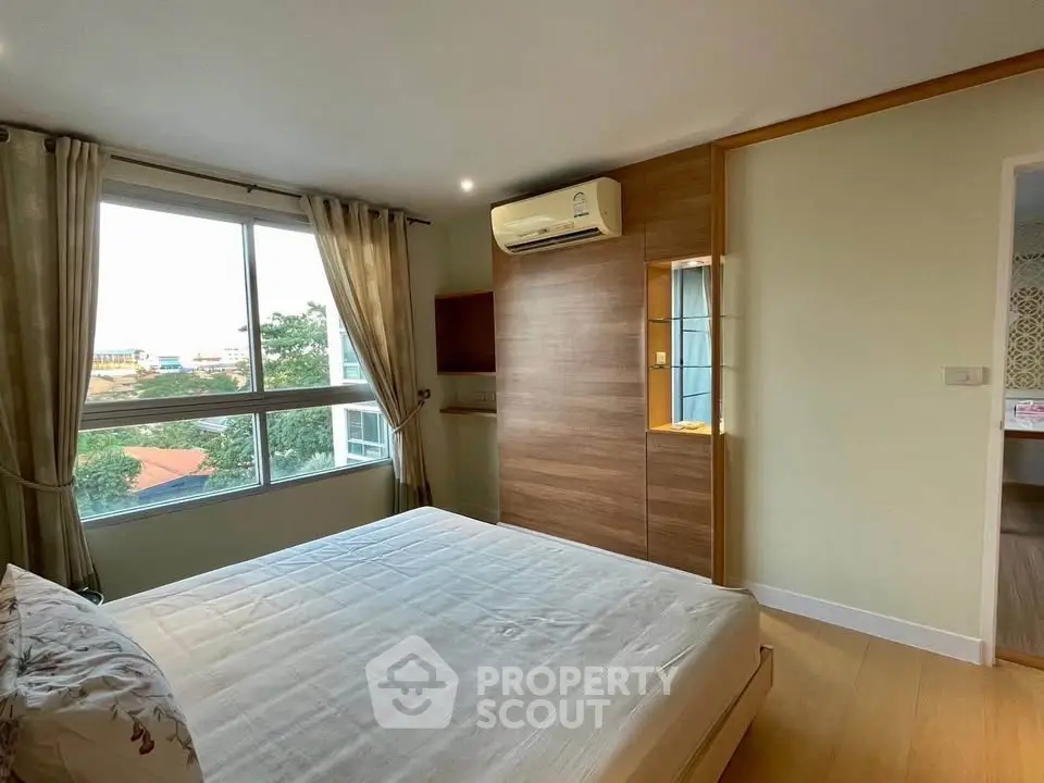 Spacious bedroom with large window and modern air conditioning unit, offering a serene view.