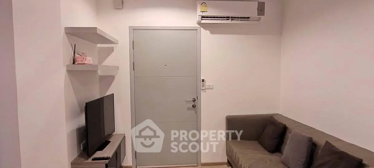 Cozy living room with modern sofa, TV, and air conditioning unit, perfect for relaxation.